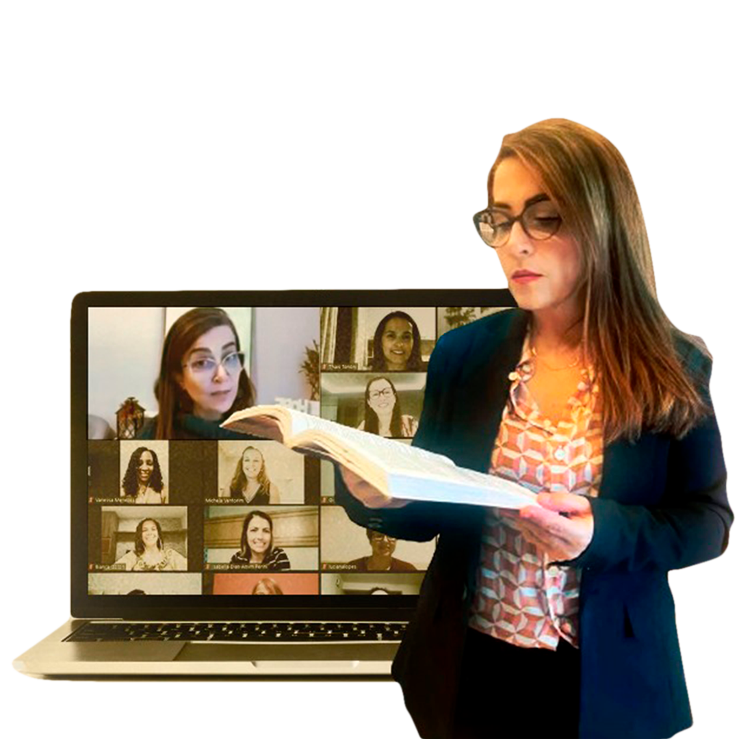 Woman wearing glasses, holding and reading an open book in front of a laptop displaying a virtual meeting with multiple participants.